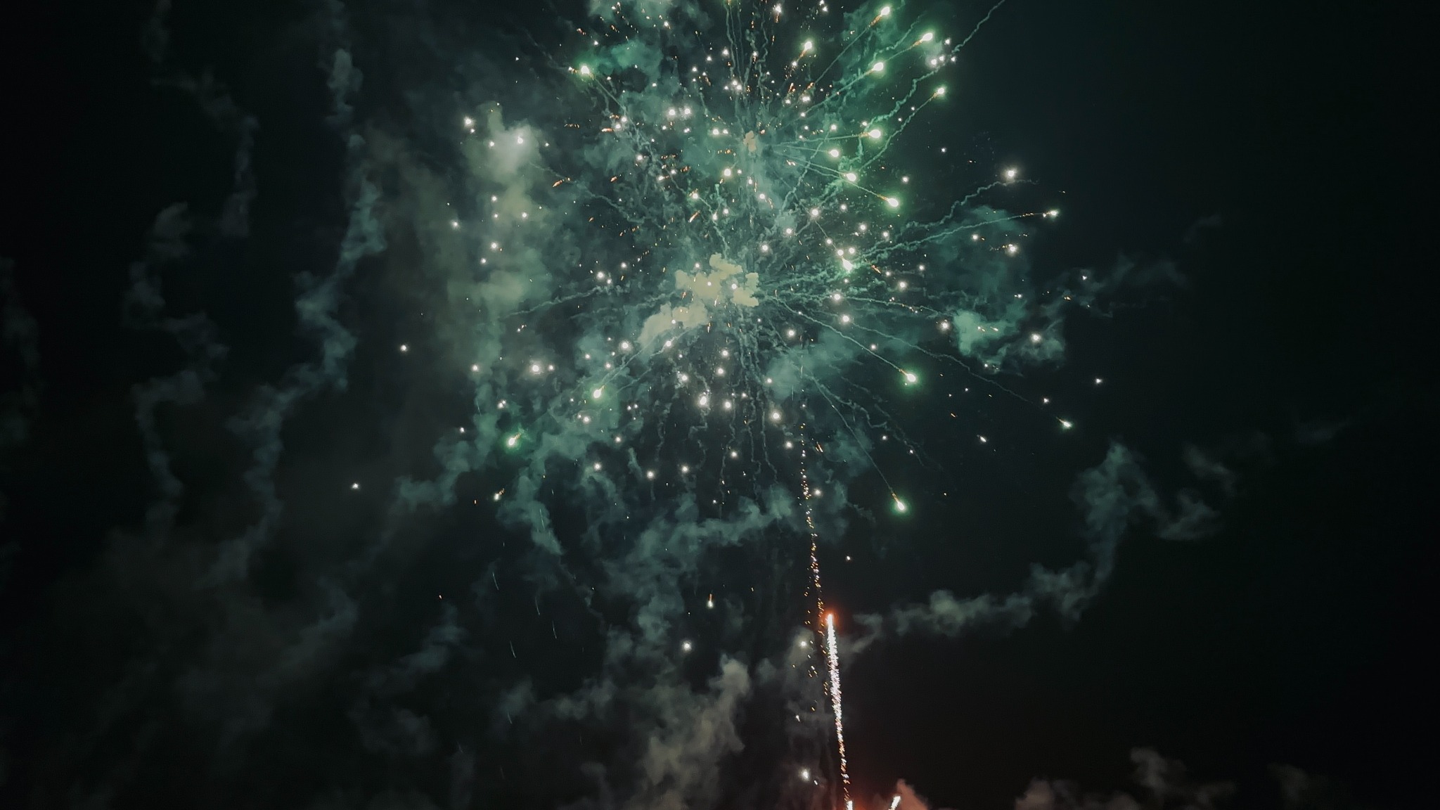 Green and white fireworks bursting overhead